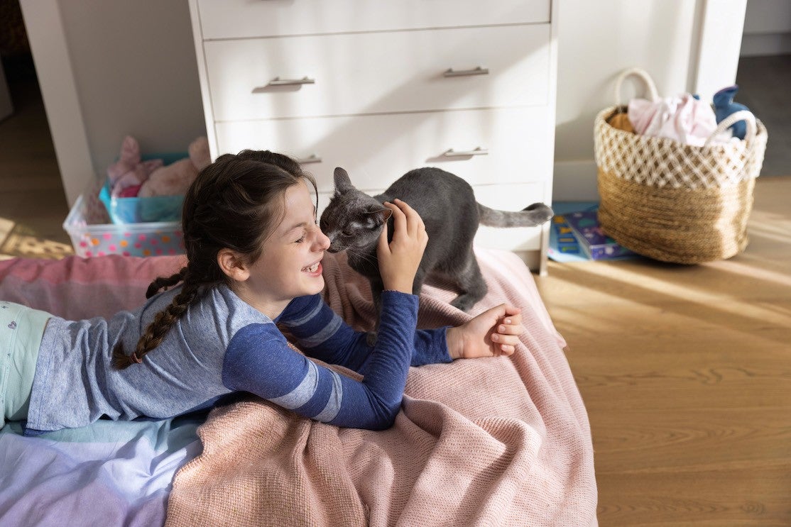 Black cat licking smiling girl on face
